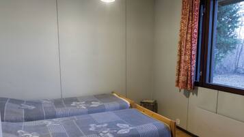 A room with two beds, a small table, and a window with curtains.