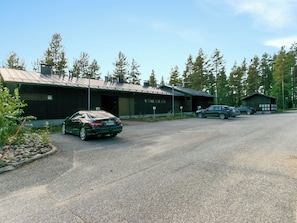 A building with a metal roof and a paved driveway. There are cars parked in front.