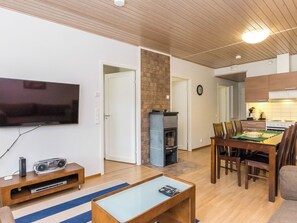 Een moderne woonkamer met een flatscreen televisie, een houten salontafel en een eethoek met een tafel en stoelen.