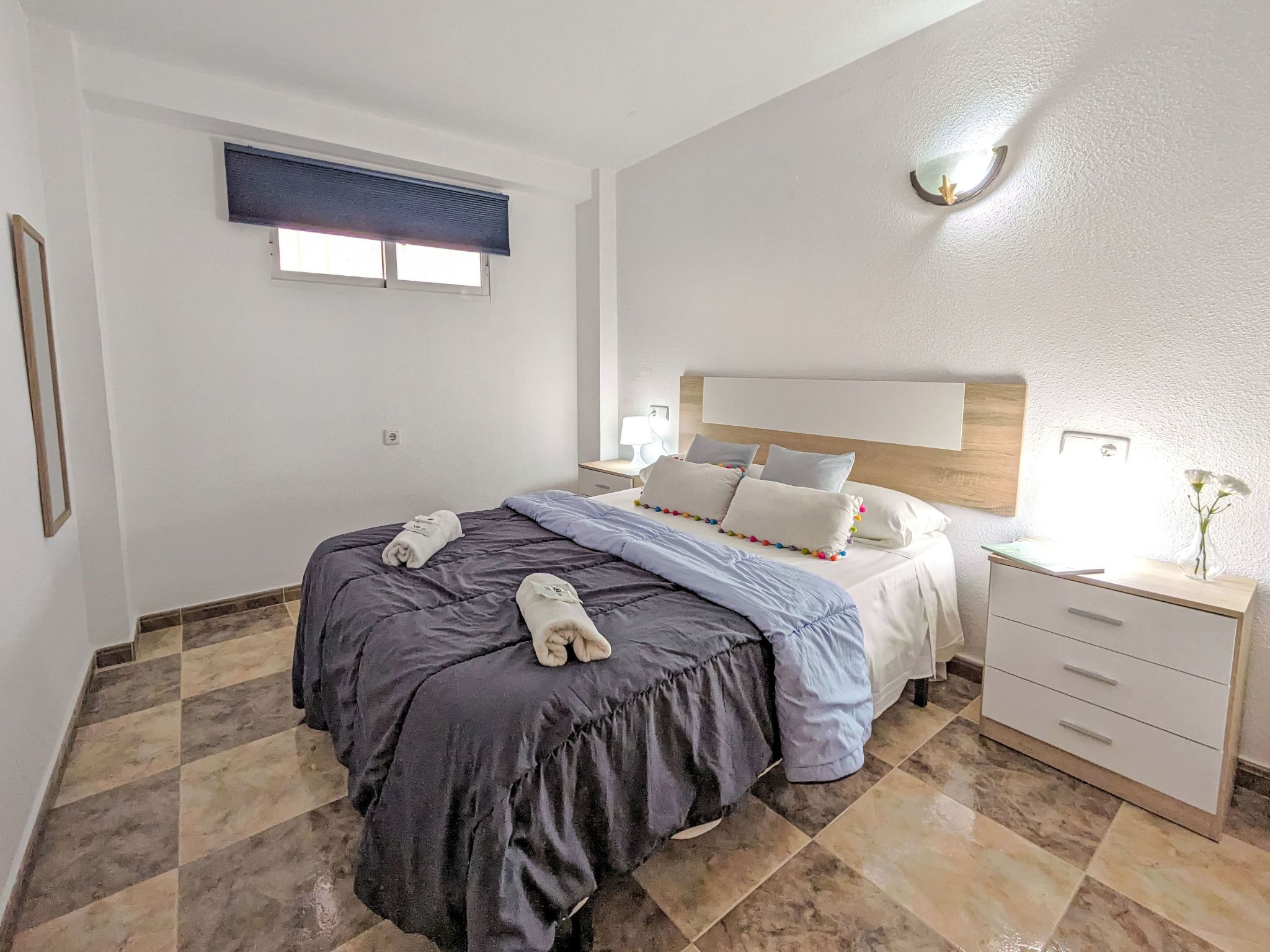 A bedroom with a bed, bedside table, and a nightstand.