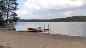Ein Sandstrand mit einem kleinen roten Boot, das an einem hölzernen Steg anliegt.