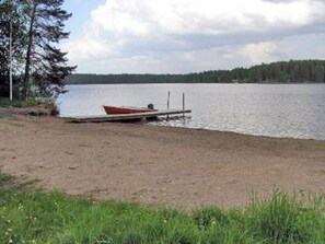 Järvi, jossa on puinen laituri ja punainen vene, joka on ankkuroitu laiturin päähän.