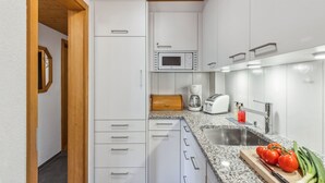 Eine kleine Küche mit weißen Schränken, einer Mikrowelle, einem Toaster und einem Spülbecken.