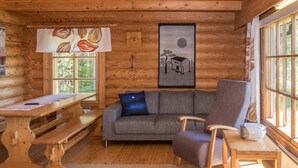 A cozy cabin interior with a wooden dining table, a sofa, and a chair.