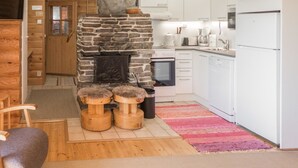 A cozy kitchen with a stone fireplace, wooden stools, and modern appliances.