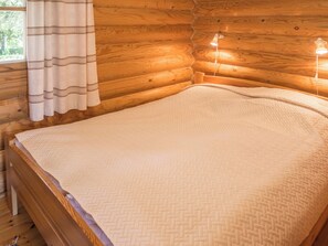 A wooden cabin interior with a bed, curtains, and a window. - Ruka-kitkan käki by Interhome (Kuusamo)