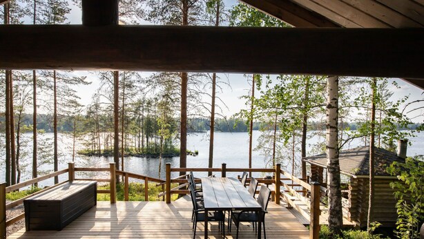 Un pontile in legno con tavolo e sedie, affacciato su un lago circondato da alberi.