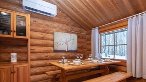 Interno di una baita in legno, con un tavolo da pranzo imbandito per quattro persone, una panca e un armadietto con vetri.