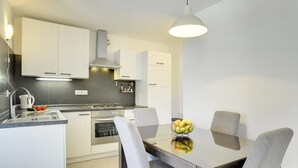 A modern kitchen with white cabinets, a stainless steel stove, and a dining table with chairs.