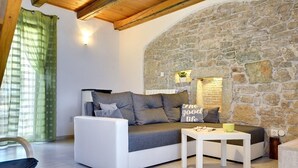 A cozy living room with a stone wall, a white sofa, and a small table.