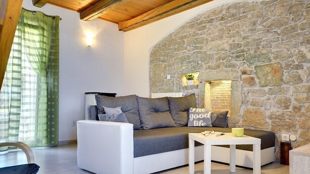 Un salón acogedor con una pared de piedra, un sofá blanco y una pequeña mesa.