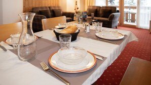 Une table à manger dressée avec des assiettes, des verres et un panier de pain.