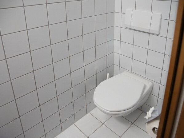 A small, clean bathroom with white tiles and a white toilet.