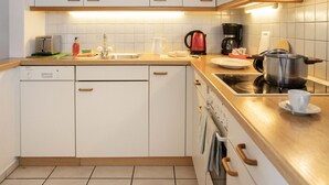 Une cuisine moderne avec des meubles blancs, un lave-vaisselle, une cuisinière et une machine à café.