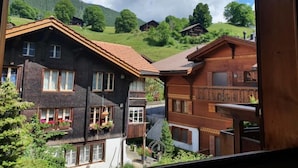 A traditional wooden house with a sloped roof, surrounded by lush greenery and a mountainous backdrop. - Chalet Abendrot apARTments by Interhome (Grindelwald)