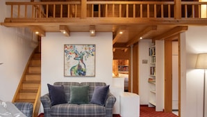 A cozy living room with a plaid sofa, a coffee table with cups, a staircase, and a bookshelf. - Chalet Abendrot apARTments by Interhome (Grindelwald)