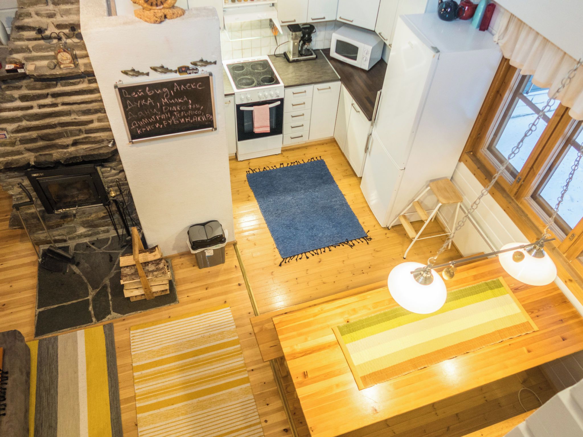A compact kitchen with a stove, microwave, and a chalkboard menu.