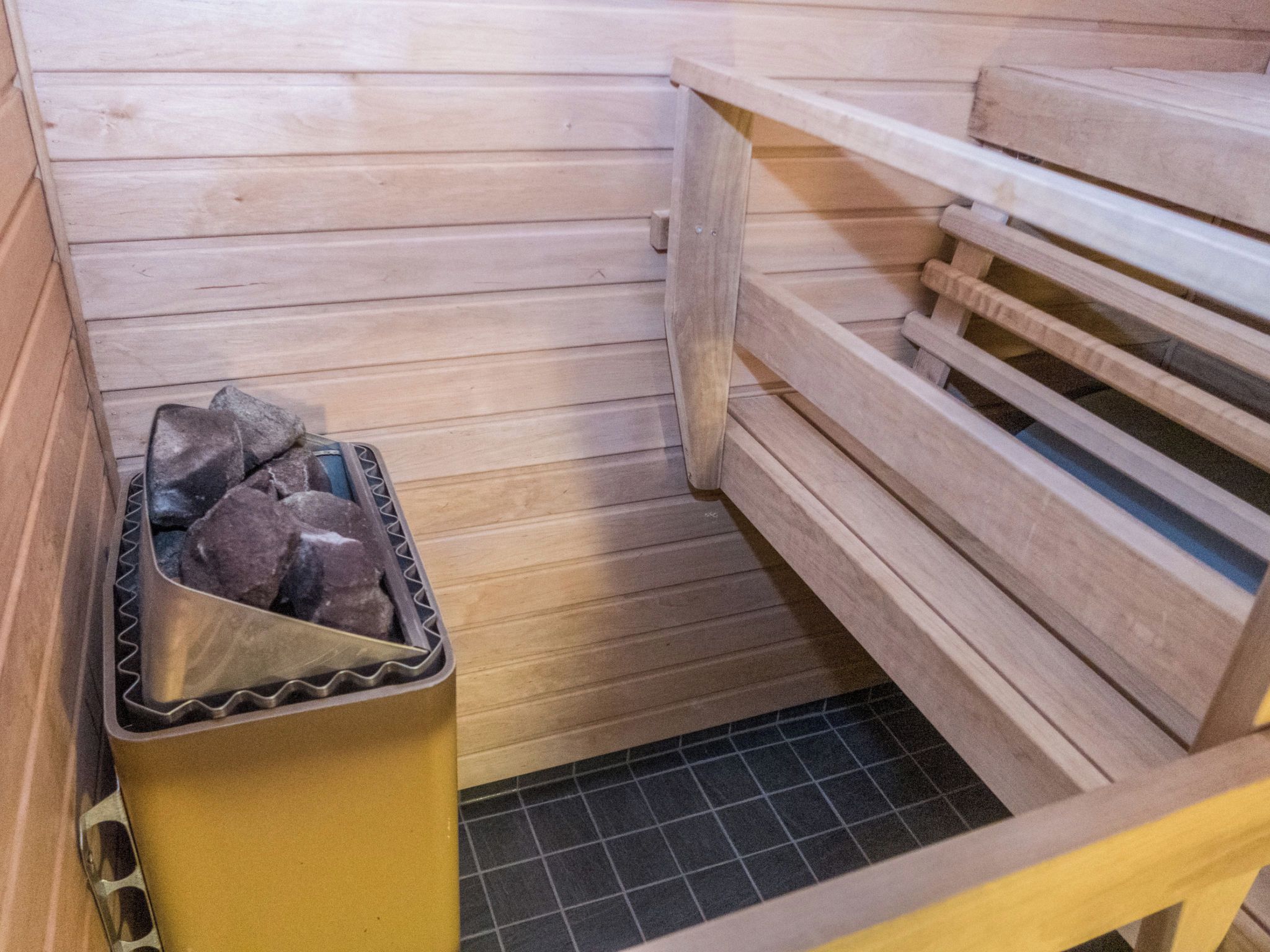 A sauna with wooden benches and a trash bin.