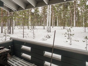 A wooden deck with a view of a snowy forest.