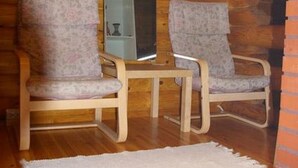 A wooden cabin interior with two upholstered chairs, a small table, and a refrigerator. - Kettupirtti by Interhome (Juva)