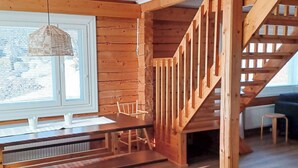 Un intérieur en bois avec un escalier, une table à manger avec des bancs et un luminaire suspendu.