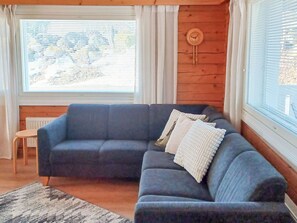 Ein Wohnzimmer mit einem blauen Sofa, einem kleinen Tisch und einem Fenster mit Jalousien.