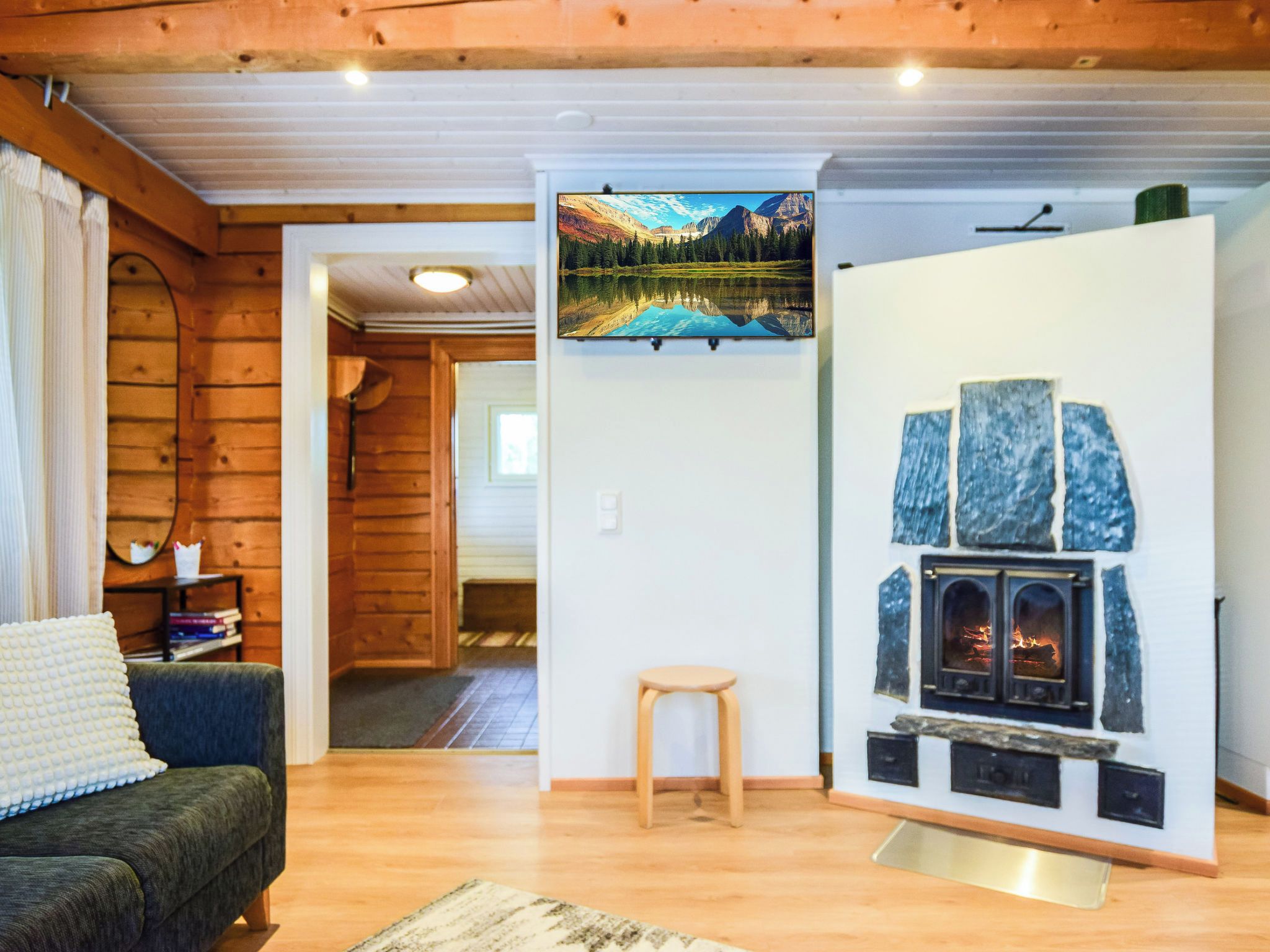 A cozy room with a fireplace, wooden walls, a sofa, and a painting of a mountain landscape.