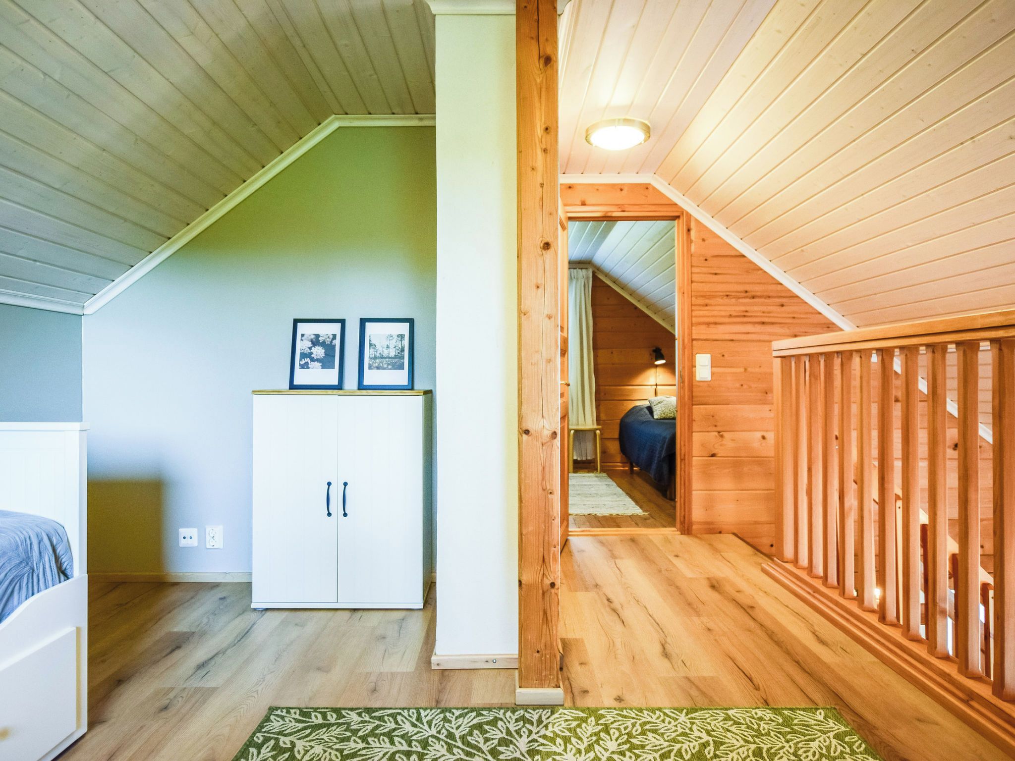 Une pièce avec un plafond en bois, une armoire blanche et un lit recouvert d’une couverture bleue.