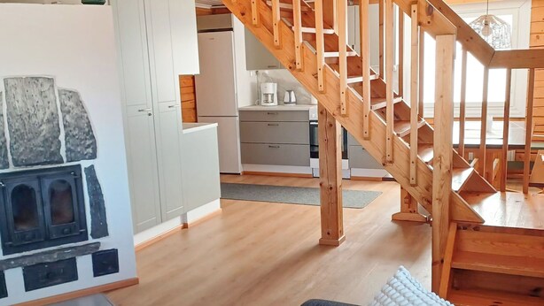 Une cuisine moderne dotée d’une cuisinière intégrée, d’un escalier en bois et d’un coin repas avec une table et des chaises.