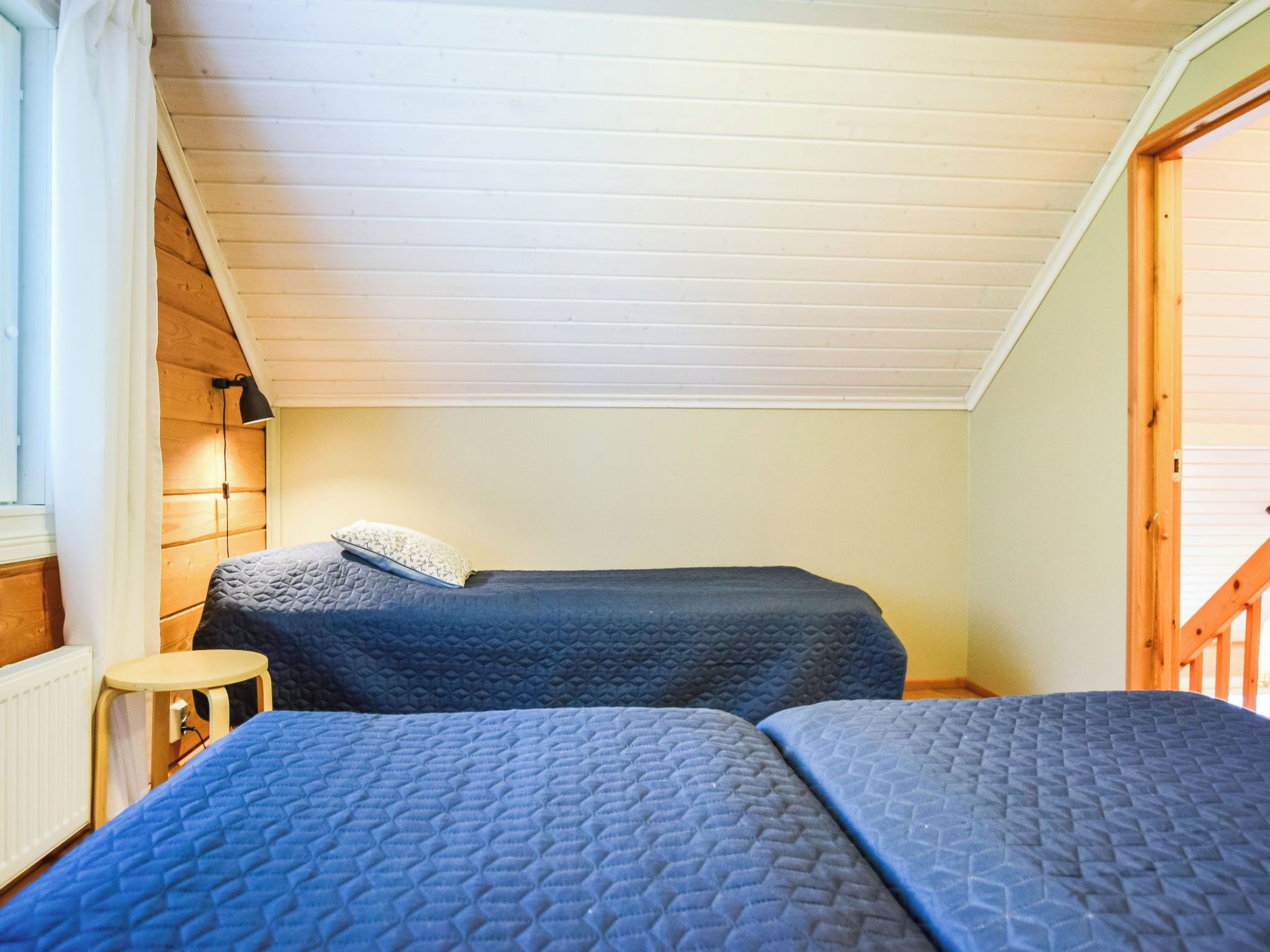 A small, cozy room with two beds, a wooden floor, and a sloped ceiling.