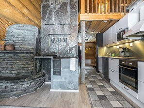 A modern kitchen with a stone wall, built-in appliances, and a checkered floor. - Juurakkopirtti by Interhome (Keuruu)