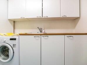 A compact kitchen with a washing machine, a sink, and cabinets. - Juurakkopirtti by Interhome (Keuruu)