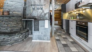 Una cocina moderna con paredes de piedra, estufa integrada y electrodomésticos de acero inoxidable.
