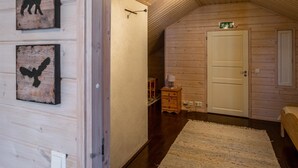 Une chambre confortable située dans les combles, avec des murs en bois, un plafond en pente et une porte portant un panneau indiquant la sortie de secours.
