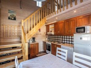 Une cuisine avec des meubles de rangement en bois, un four à micro-ondes, une cuisinière et un réfrigérateur.