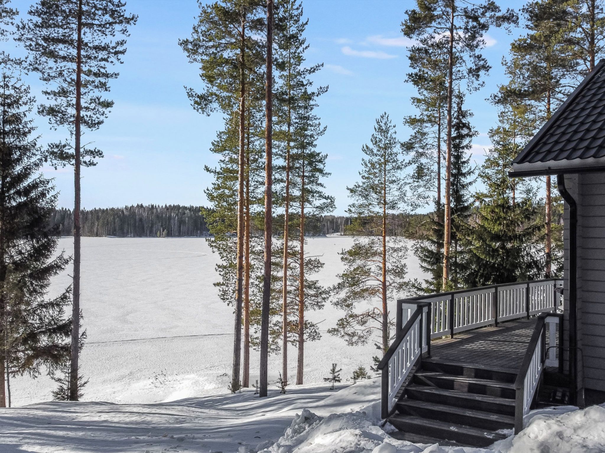 Puinen portaikko johtaa rakennukseen, josta avautuu näkymä lumiseen maisemaan ja korkeisiin mäntyihin.