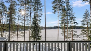 En terrasse med udsigt over et sneklædt landskab og høje træer.