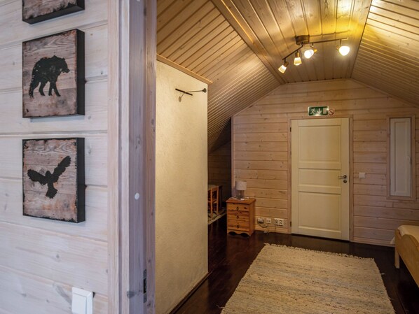 Un dormitorio acogedor en el ático, con paredes de madera, techo inclinado y una puerta con letrero de salida de emergencia.