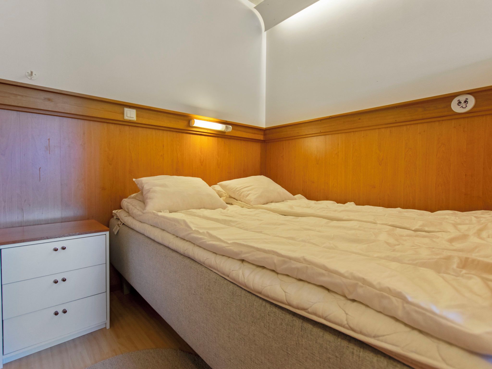 A bedroom with a single bed, a nightstand, and a dresser.