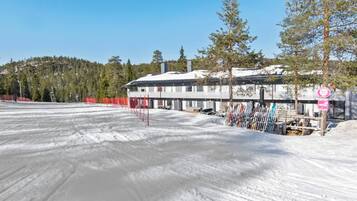 A snow-covered ski resort with a building that has multiple windows and a ski lift nearby.