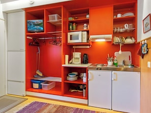 Eine kleine Küche mit Mikrowelle, Kaffeemaschine und einem Kühlschrank.
