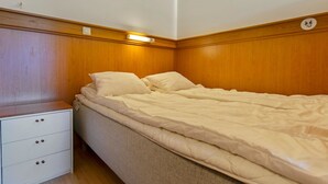Ein Schlafzimmer mit einem hölzernen Kopfende, einem Einzelbett mit weißer Bettwäsche und einem Nachttisch mit Schubladen.