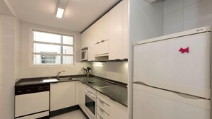 A modern kitchen with white cabinets, a built-in oven, a microwave, and a refrigerator. - Vila Olímpica: Sant Martí - Sardenya by Interhome (Barcelona)