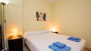 A hotel room with a bed, two bedside lamps, a floor lamp, and a painting on the wall. - Vila Olímpica: Sant Mart í - Sardenya by Interhome (Barcelona)