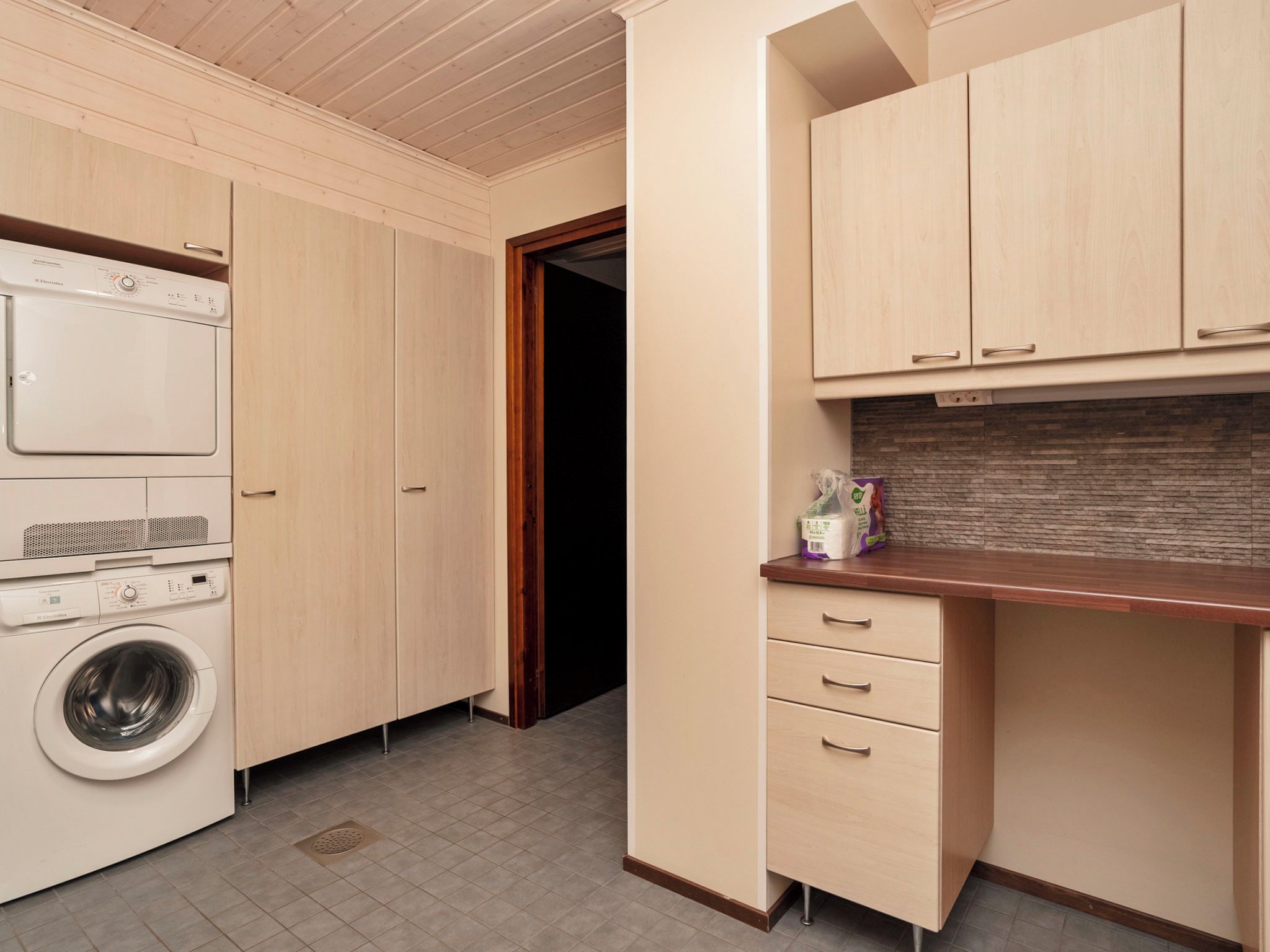 A laundry room with a washing machine, a dryer, and wooden cabinets.