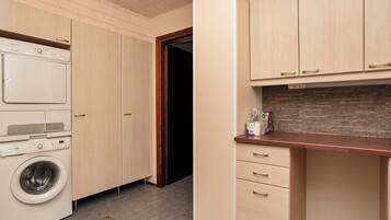 A laundry room with a washing machine, a dryer, and wooden cabinets.