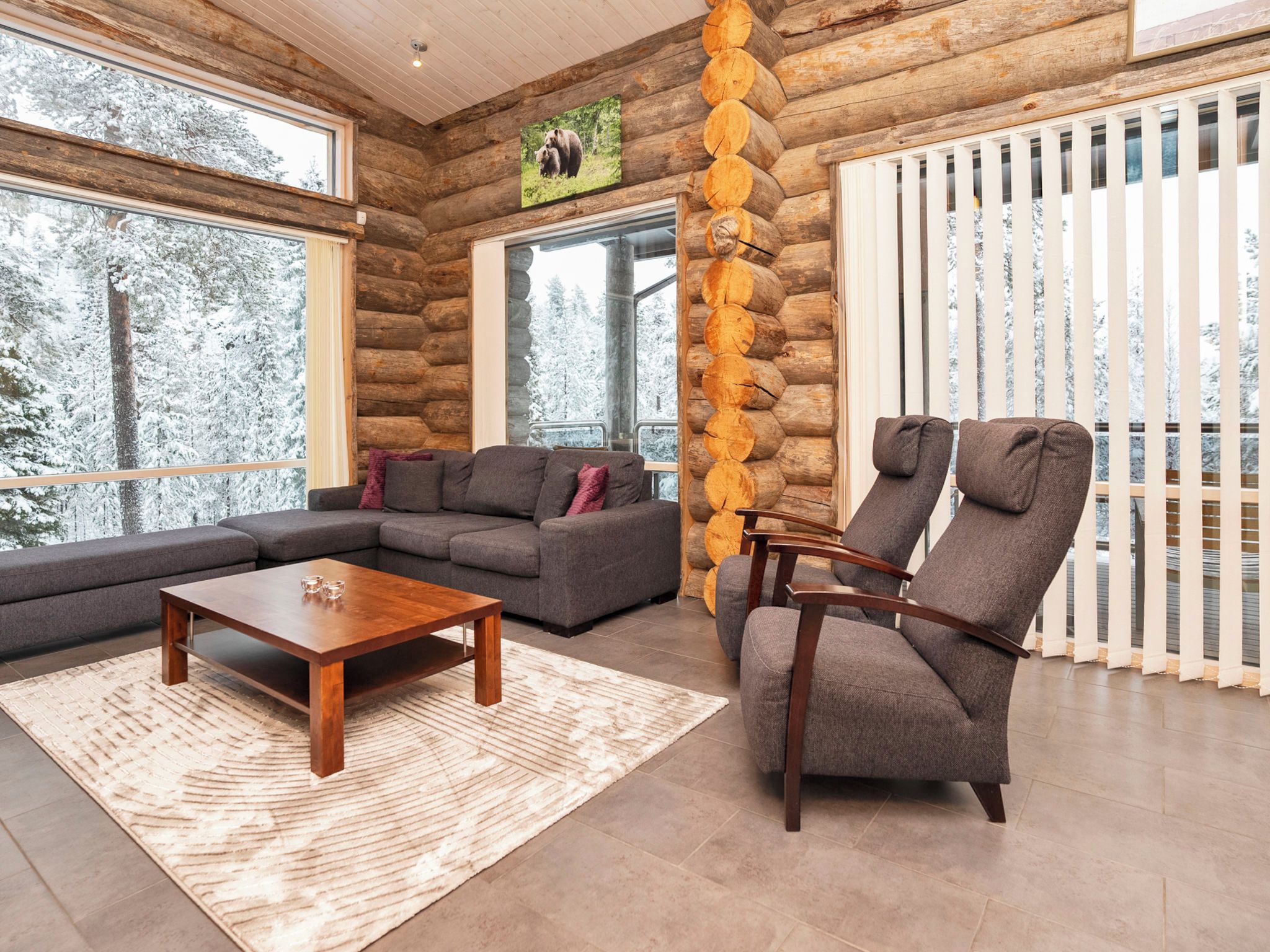 Een interieur van een blokhut met een hoekbank, een houten salontafel en een fauteuil.