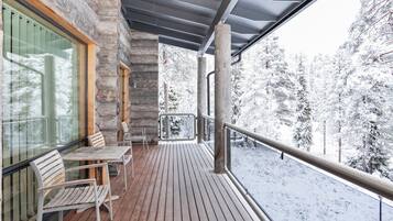 Een houten terras met uitzicht op met sneeuw bedekte bomen.