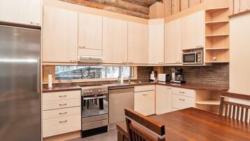 Een moderne keuken met houten kastjes, roestvrijstalen apparatuur en een betegelde achterwand.