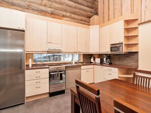 Een moderne keuken met houten kastjes, roestvrijstalen apparatuur en een betegelde achterwand.
